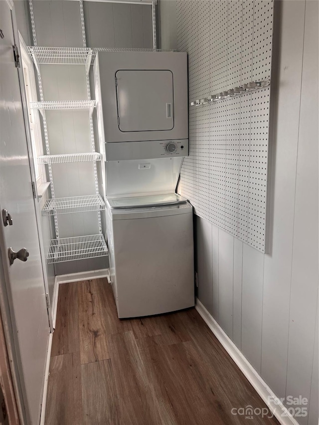 clothes washing area with stacked washer and clothes dryer and dark hardwood / wood-style floors