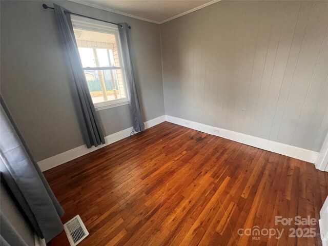 unfurnished room with ornamental molding and wood-type flooring