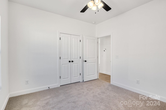 unfurnished bedroom featuring ceiling fan, light colored carpet, and a closet