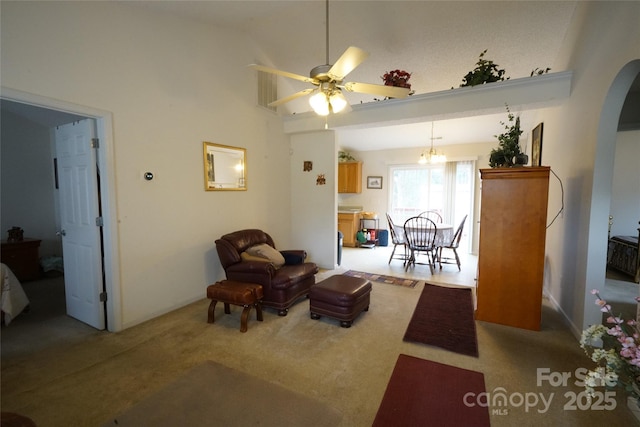 sitting room with carpet, vaulted ceiling, and ceiling fan with notable chandelier