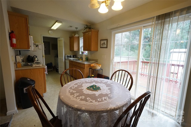 dining space with vaulted ceiling, a chandelier, and sink