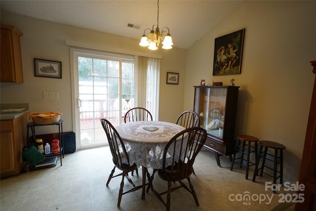 dining space featuring vaulted ceiling and an inviting chandelier