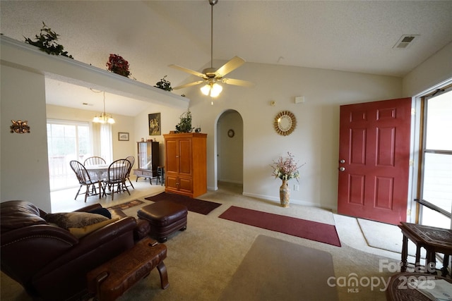 carpeted living room with ceiling fan with notable chandelier, plenty of natural light, and lofted ceiling