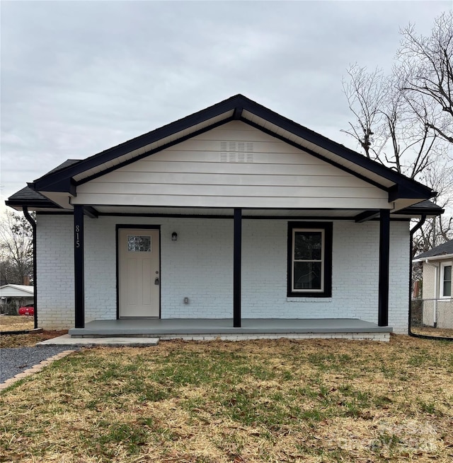 back of property with a yard and a porch