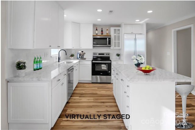 kitchen with white cabinets, sink, a kitchen island, and appliances with stainless steel finishes