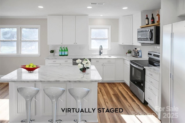 kitchen featuring white cabinetry, a breakfast bar, stainless steel appliances, and sink