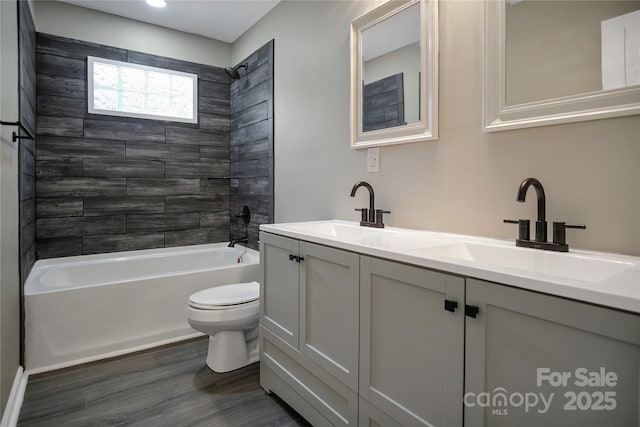 full bathroom with hardwood / wood-style flooring, tiled shower / bath combo, toilet, and vanity