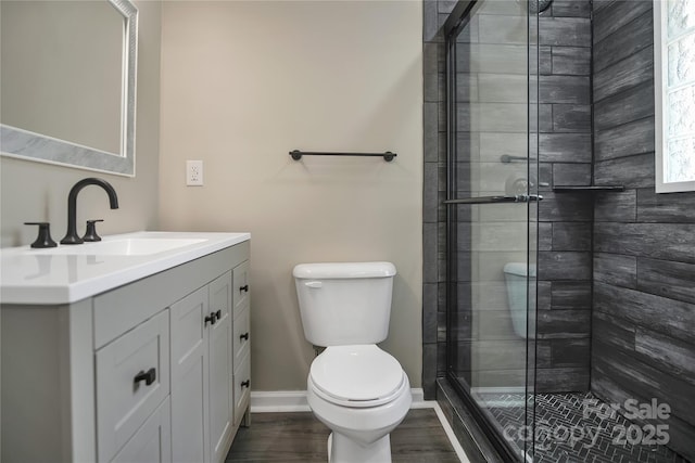 bathroom with hardwood / wood-style floors, vanity, toilet, and a shower with door