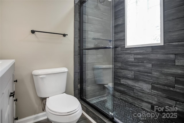 bathroom featuring a shower with door, vanity, and toilet