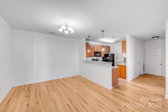 kitchen with light hardwood / wood-style flooring, a notable chandelier, kitchen peninsula, pendant lighting, and black appliances