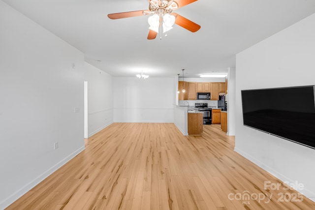 unfurnished living room featuring ceiling fan with notable chandelier and light wood-type flooring