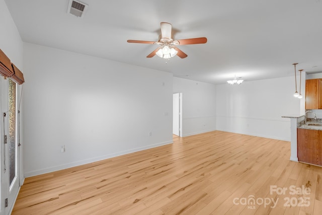 unfurnished room with ceiling fan with notable chandelier, light hardwood / wood-style floors, and sink