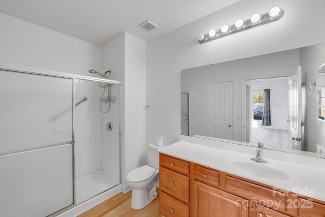 bathroom with hardwood / wood-style floors, vanity, toilet, and walk in shower