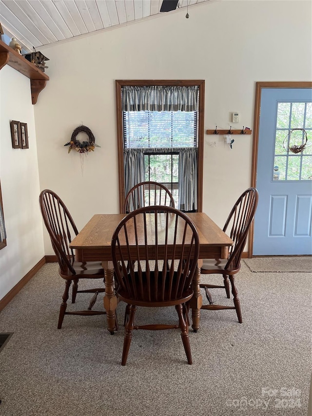 carpeted dining space with vaulted ceiling