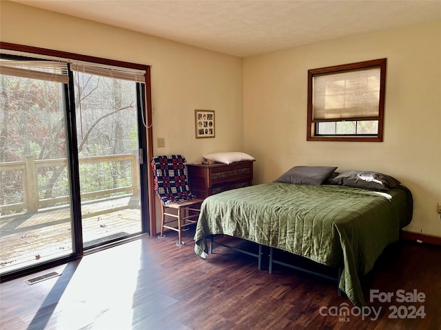 bedroom featuring access to outside, dark hardwood / wood-style flooring, and a textured ceiling