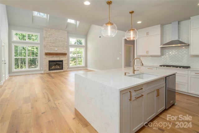 kitchen featuring wall chimney exhaust hood, plenty of natural light, sink, and decorative light fixtures