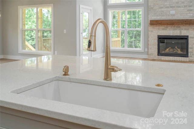 room details with light stone countertops, sink, and a brick fireplace