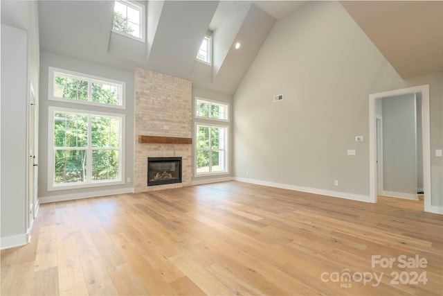 unfurnished living room featuring light hardwood / wood-style flooring, high vaulted ceiling, and plenty of natural light