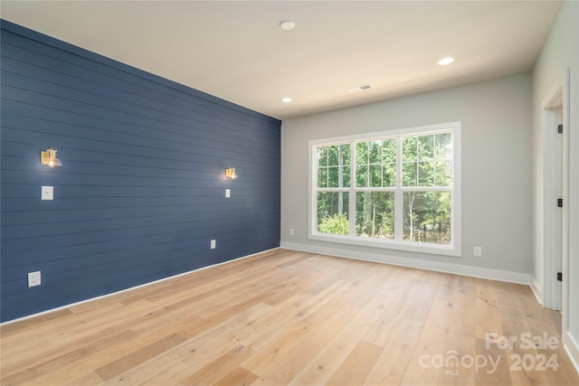 empty room featuring light wood-type flooring and wooden walls