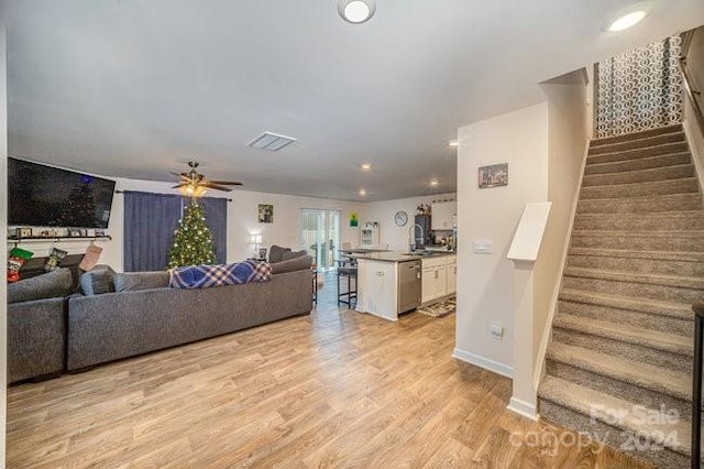 living room featuring ceiling fan, light wood-type flooring, and sink