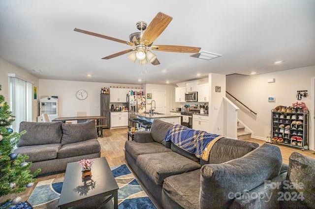 living room featuring ceiling fan, sink, and light hardwood / wood-style flooring