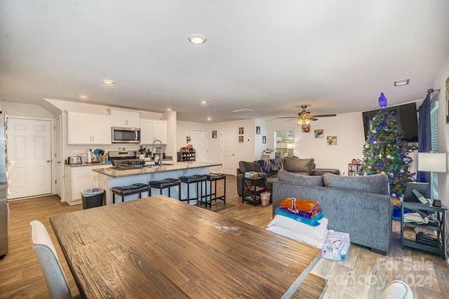 dining area featuring ceiling fan, sink, and light hardwood / wood-style flooring