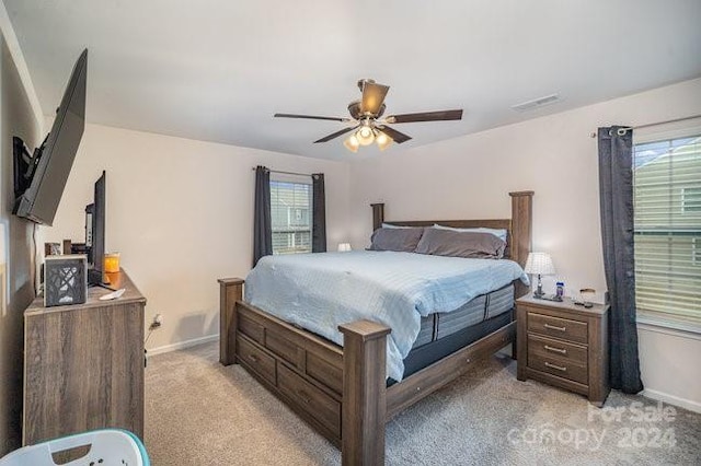 carpeted bedroom featuring ceiling fan and multiple windows