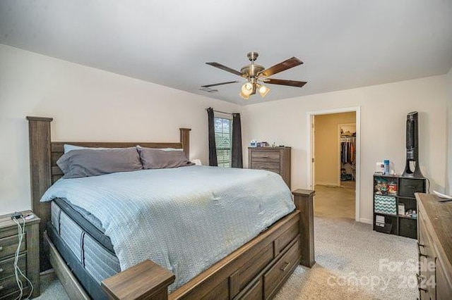 carpeted bedroom with ceiling fan and a spacious closet