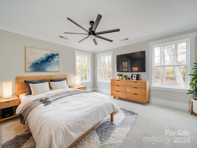 bedroom with ceiling fan, light colored carpet, ornamental molding, and multiple windows