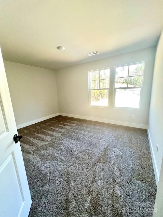 spare room featuring dark carpet