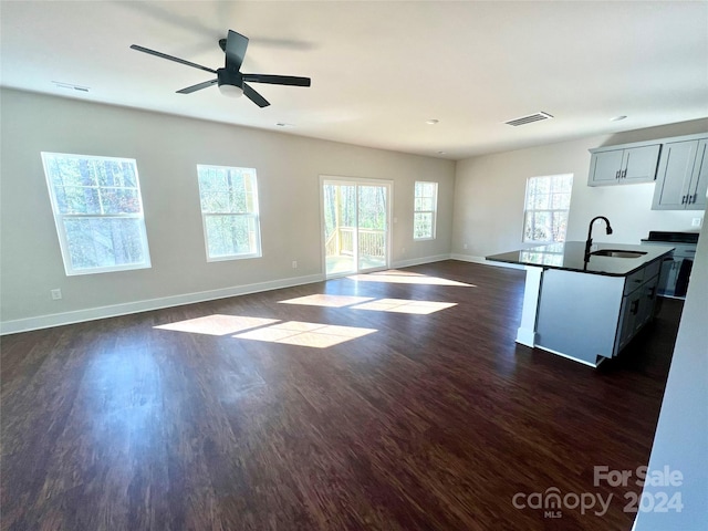 kitchen with ceiling fan, sink, an island with sink, and dark wood-type flooring