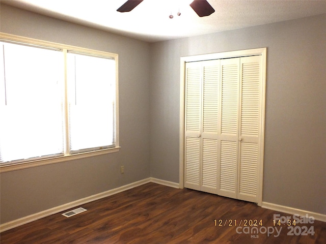 unfurnished bedroom with a closet, ceiling fan, and dark wood-type flooring