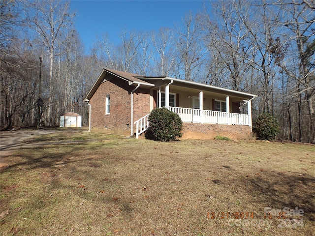 view of front of house with covered porch, a garage, a front lawn, and an outdoor structure