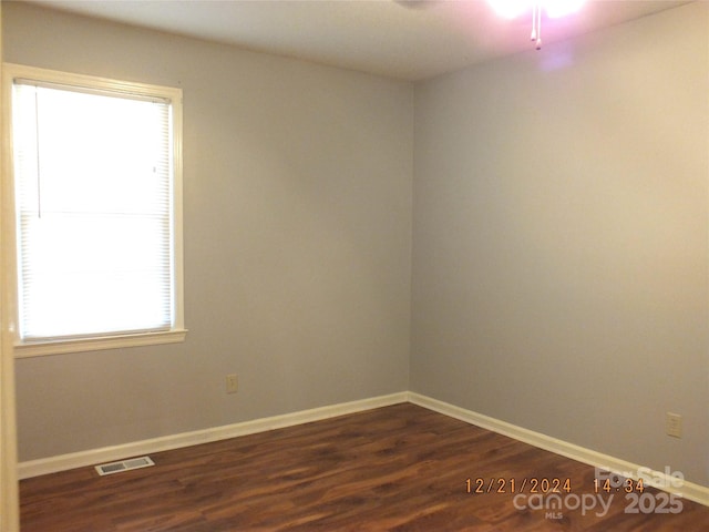 spare room featuring dark wood-style floors, visible vents, and baseboards