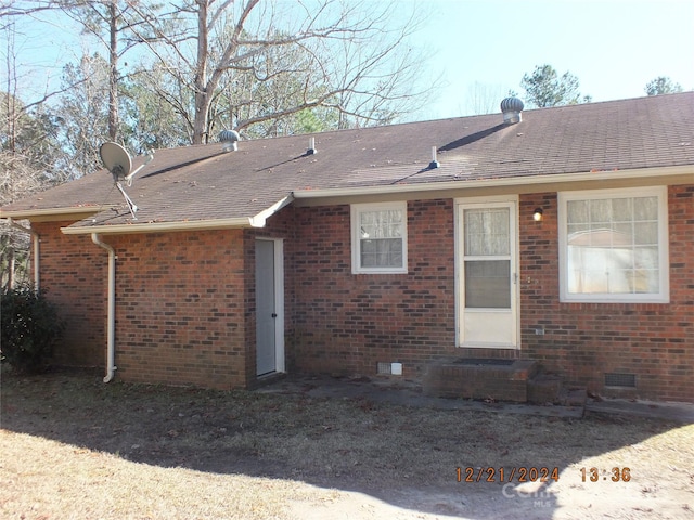 rear view of house featuring entry steps, brick siding, crawl space, and a shingled roof