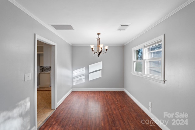 spare room featuring crown molding, wood-type flooring, and a notable chandelier