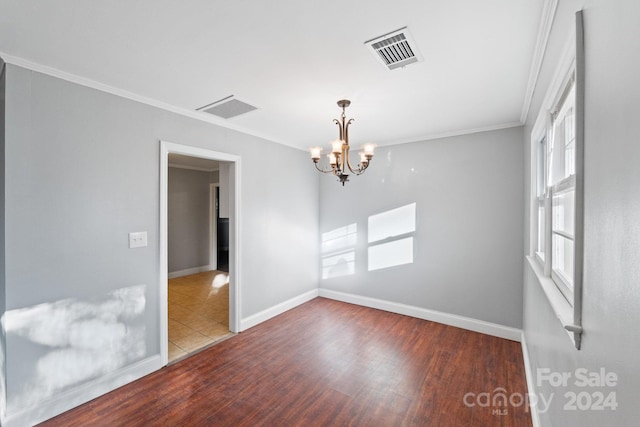 empty room with a chandelier, wood-type flooring, and crown molding