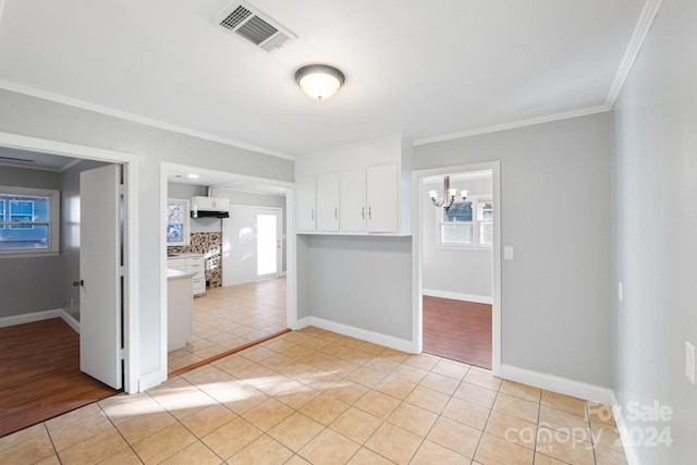 tiled spare room with crown molding and a notable chandelier