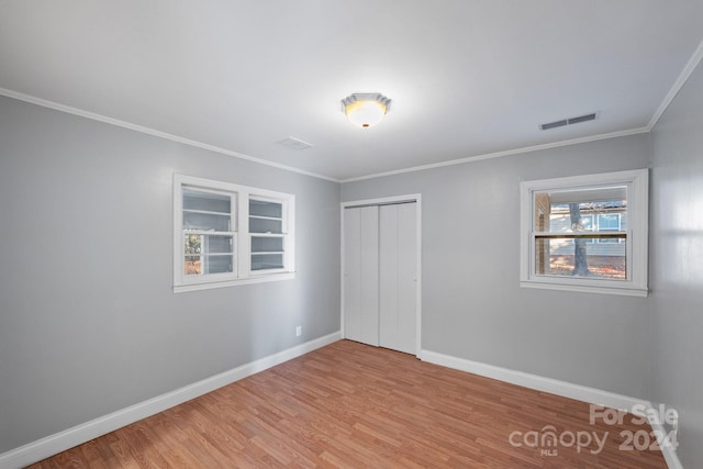 unfurnished bedroom with light wood-type flooring, a closet, and crown molding