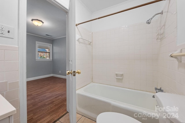 bathroom with crown molding, hardwood / wood-style flooring, tiled shower / bath combo, and toilet