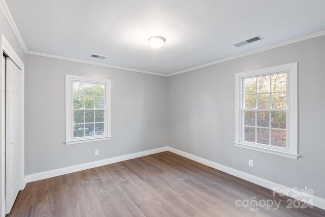 spare room featuring a healthy amount of sunlight, wood-type flooring, and ornamental molding