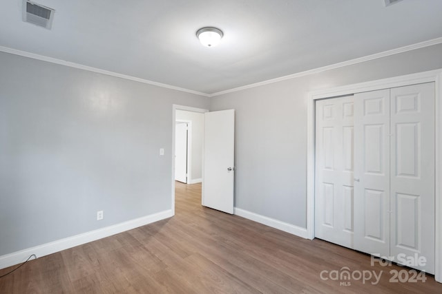 unfurnished bedroom with crown molding, a closet, and light hardwood / wood-style floors