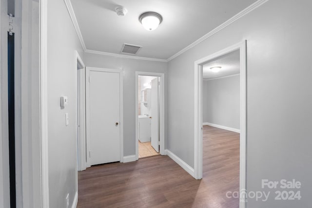 hallway with wood-type flooring, a textured ceiling, and ornamental molding