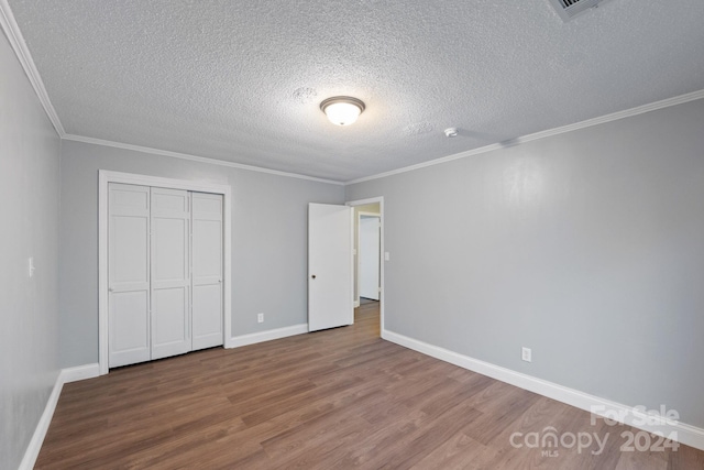 unfurnished bedroom featuring crown molding, a closet, wood-type flooring, and a textured ceiling