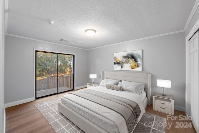 bedroom featuring access to outside, light hardwood / wood-style flooring, a textured ceiling, and ornamental molding