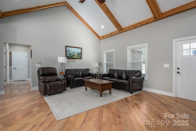 living room with ceiling fan, light hardwood / wood-style floors, beam ceiling, and high vaulted ceiling