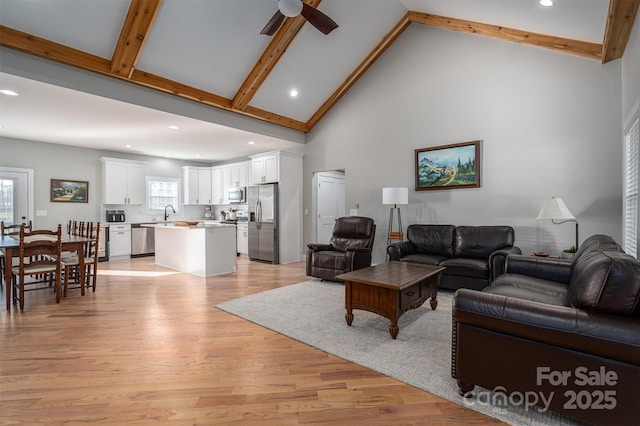 living room with beamed ceiling, light hardwood / wood-style floors, high vaulted ceiling, and ceiling fan