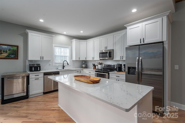 kitchen with appliances with stainless steel finishes, light stone counters, white cabinetry, and sink