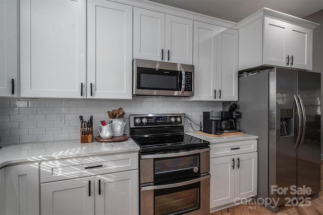 kitchen featuring white cabinetry, decorative backsplash, light stone counters, and appliances with stainless steel finishes