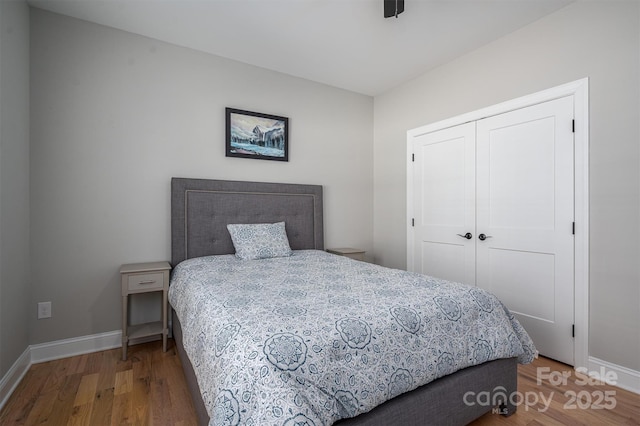 bedroom featuring ceiling fan, a closet, and hardwood / wood-style flooring